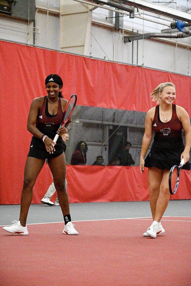 (From left) Graduate Alana Smith and freshman Diana Schnaider share a laugh during their doubles match against Oklahoma players Carmen Corley and Ivana Corley at J.W. Isenhour Tennis Center on Saturday, Feb. 4, 2023. Smith and Shnaider won their doubles match. NC State beat Oklahoma 6-1.
