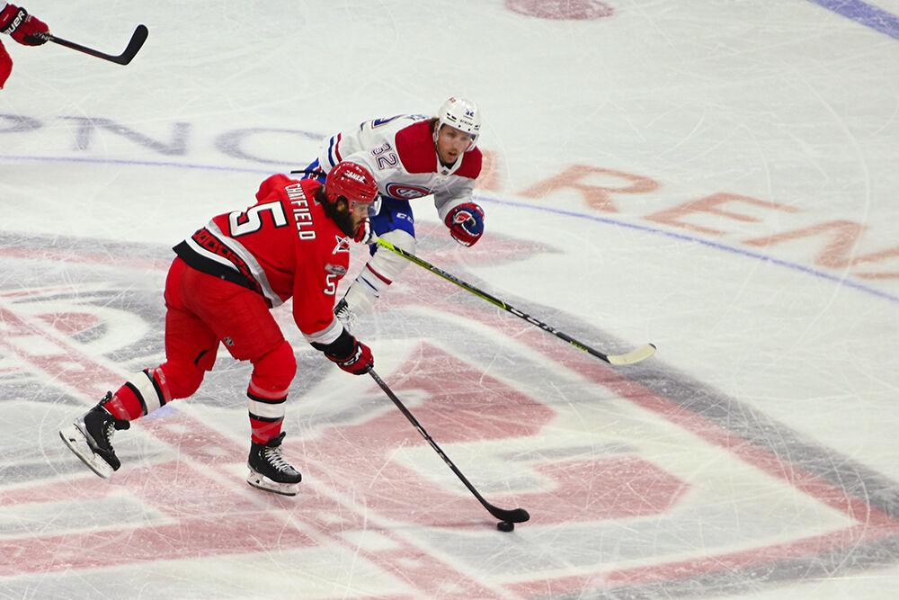 Carolina Hurricanes defenseman Jalen Chatfield dribbles the puck away from opponent during the game against the Montreal Canadiens in PNC Arena on Thursday, Feb. 16, 2023. The Hurricanes won 6-2.