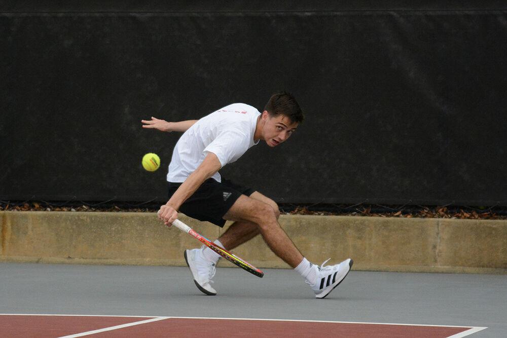 Redshirt sophomore Braden Shick crouches to reach a ball during the match against Elon University at Dail Outdoor Tennis Stadium on Sunday, Feb. 26, 2023. Shick won his singles match 2-0 and the Wolfpack beat the Phoenix 5-2.