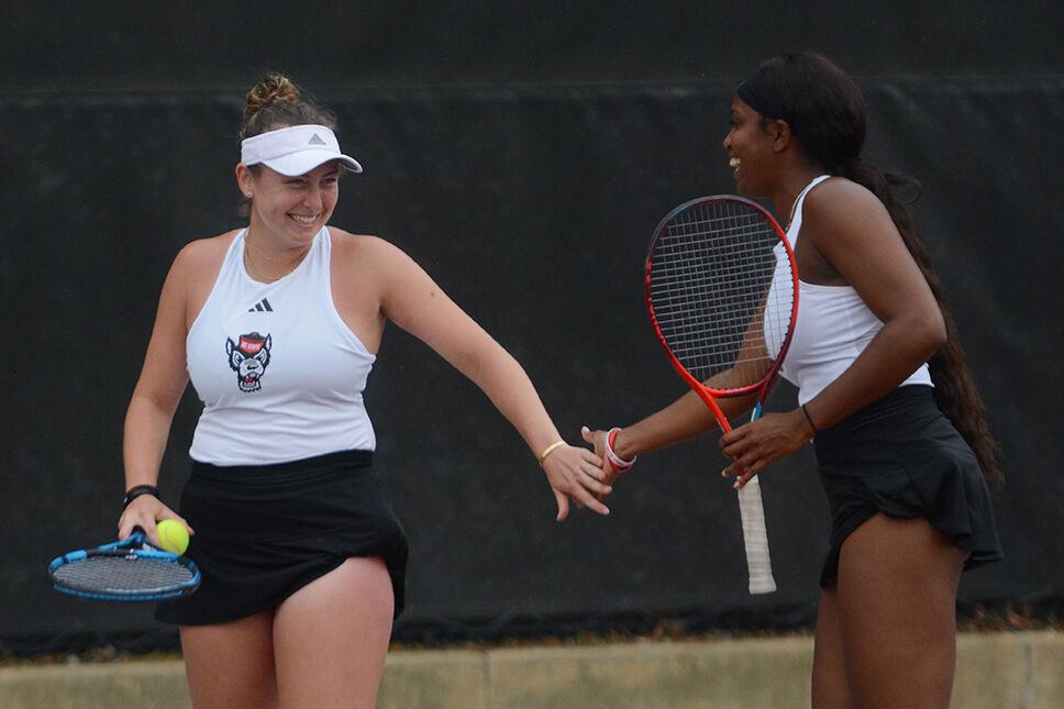 (From left) Junior Abigail Rencheli and graduate student Alana Smith high-five during their doubles match against East Carolina University at the Dail Outdoor Tennis Stadium on Friday, March 31, 2023. The Wolfpack beat ECU 7-0.