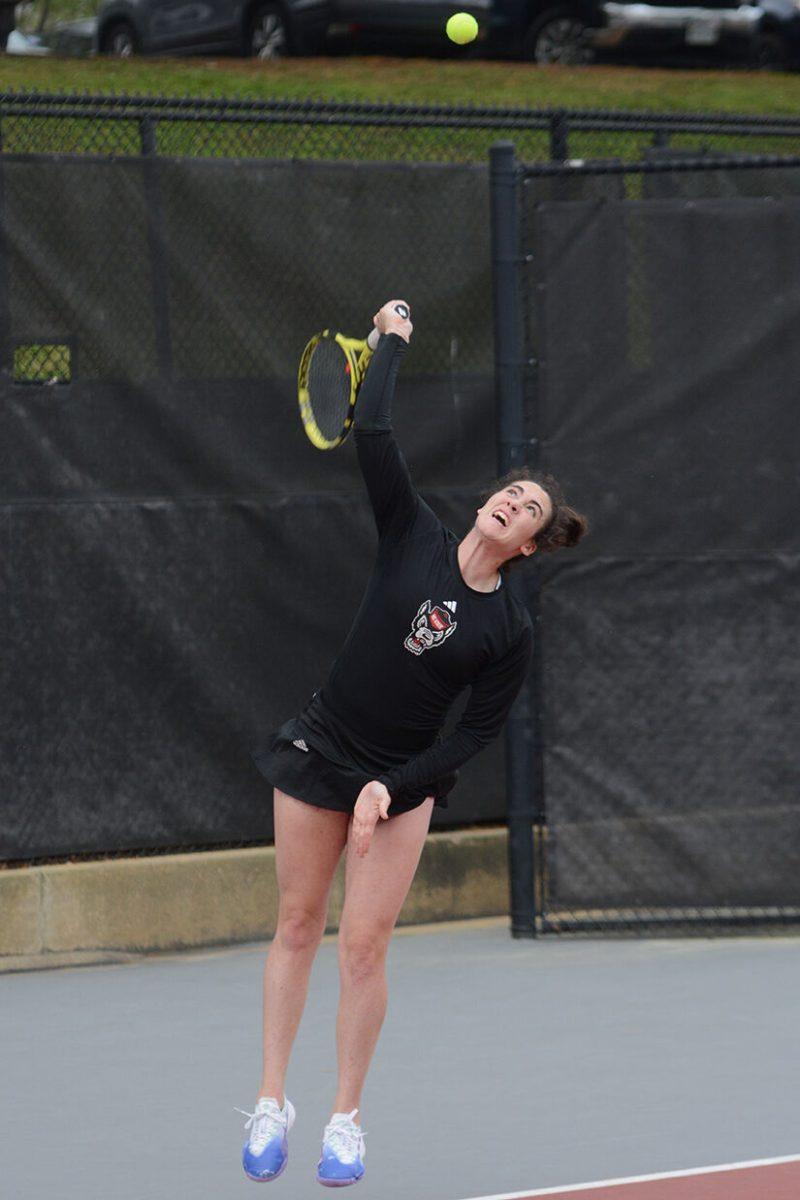 Graduate Nell Miller serves the ball in her doubles match against East Carolina University at the Dail Outdoor Tennis Stadium on Friday, March 31, 2023. The Wolfpack beat ECU 7-0.