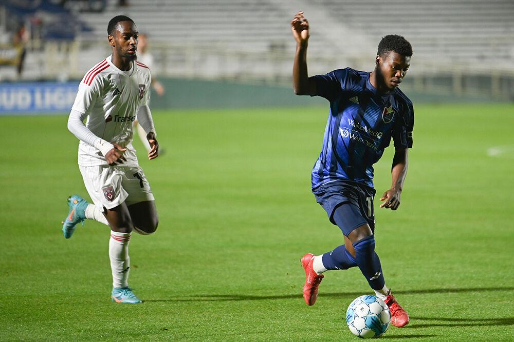 North Carolina FC forward Shakeem Adams dribbles the ball away from a Chattanooga Red Wolves opponent towards the goal at Sahlen's Stadium in WakeMed Soccer Park on Friday, April 21, 2023. NCFC beat the Red Wolves 3-0.