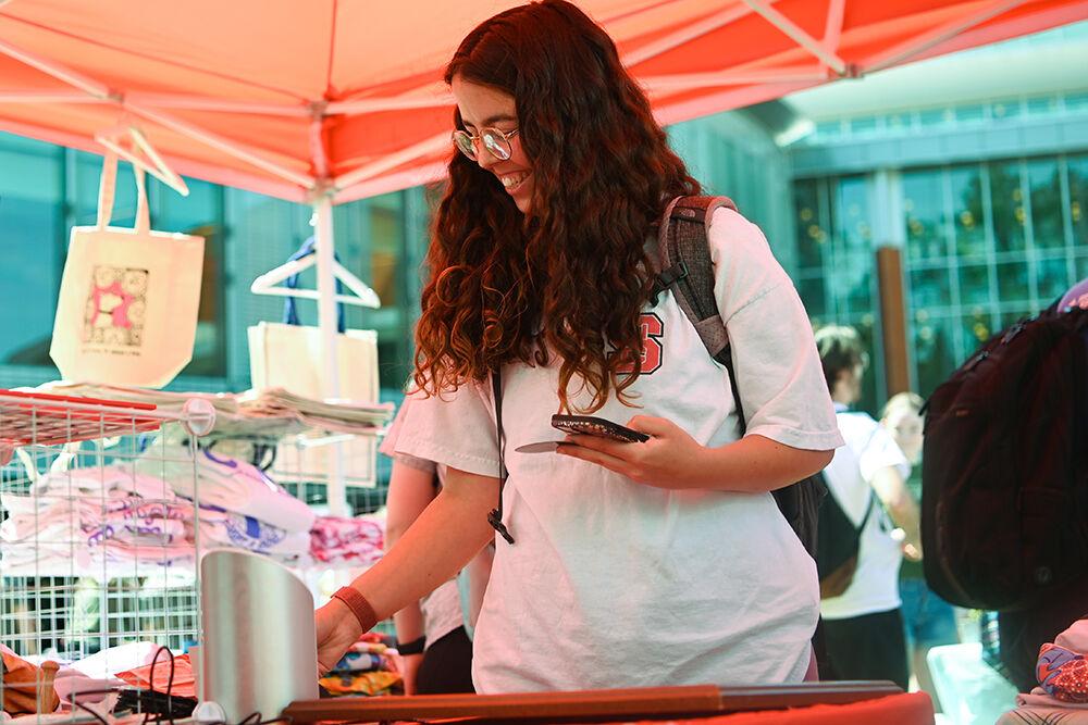 Chloe Roy, a fourth-year studying communications, shops at Binky and Bell, a company the helps local animal rescues and shelters, at the Earth Fair on Stafford Commons on Wednesday, April 12, 2023. The Earth Fair was an annual event that promoted sustainability in a multitude of facets such as food, water, transportation, wellness and more.