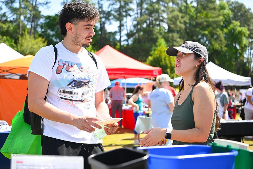 Julian Mosqueda, a first-year studying electrical engineering, talks with Ann Winstead, a fourth-year studying environmental science and political science, about properly sorting waste products at the Earth Fair on Stafford Commons on Wednesday, April 12, 2023. The Earth Fair was an annual event that promoted sustainability in a multitude of facets such as food, water, transportation, wellness and more.