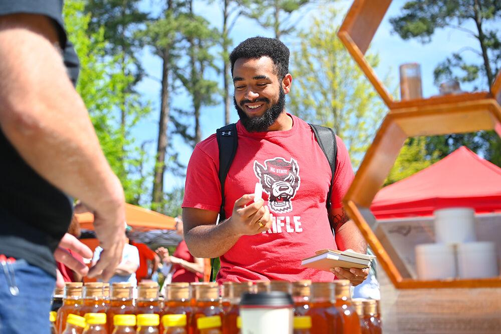 Carlos Moorse, a fourth-year studying psychology, tries samples of honey at the Earth Fair on Stafford Commons on Wednesday, April 12, 2023. The Earth Fair was an annual event that promoted sustainability in a multitude of facets such as food, water, transportation, wellness and more.