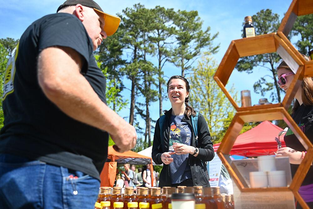 Hannah Justice, a first-year studying accounting, tries samples of honey at the Earth Fair on Stafford Commons on Wednesday, April 12, 2023. The Earth Fair was an annual event that promoted sustainability in a multitude of facets such as food, water, transportation, wellness and more.