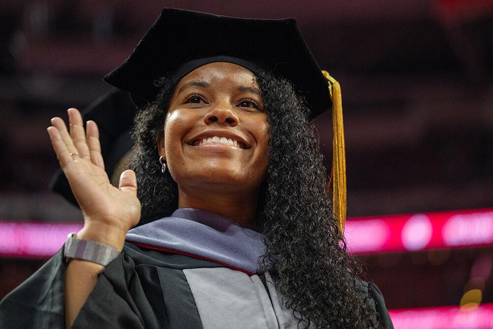 Affrika Sanford, a doctoral student in veterinary medicine, waves to family and friends during&#160;the Spring Commencement Ceremony in PNC Arena on Saturday, May 6, 2023. Sanford was a member of the student-run Carnivore Conservation Crew of wolf-watchers during her time at NC State.