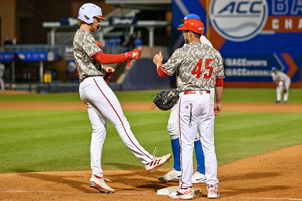 Graduate outfielder Parker Nolan gives a fist bump to his coach after a walk to first base during the ACC Tournament game against Duke at Durham Bulls Athletic Park on Tuesday, May 23, 2023. Nolan had two runs for NC State. NC State beat Duke 8-7.