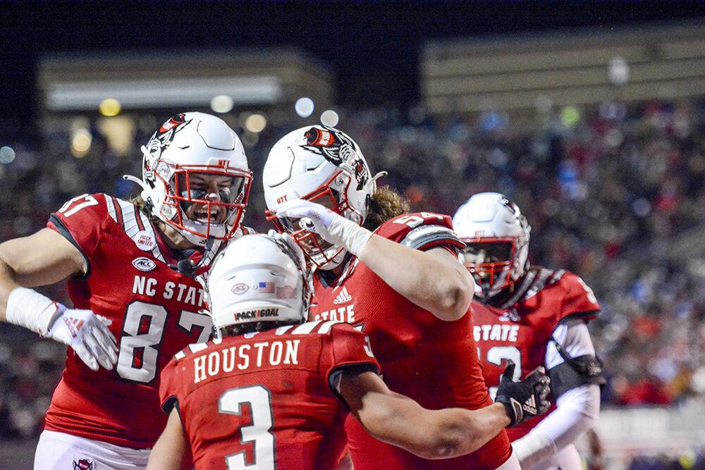 Redshirt freshman tight end Kameron Walker and redshirt freshman offensive lineman Dylan McMahon congratulate sophomore running back Jordan Houston after a play in the game against UNC-Chapel Hill on Friday, Nov. 26, 2021 at Carter-Finley Stadium. The Wolfpack scored in the last few minutes of the game and beat the Tar Heels 34-30.