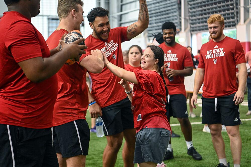 Meredith Grieci high-fives NC State football players after hitting the target of a throwing drill during Victory Day at the Close-King Indoor Practice Facility on Friday, Aug. 4, 2023. Victory Day was an event held by GiGi's Playhouse and the NC State football team that gave young people with Down Syndrome an opportunity to run drills with players and enjoy a moment in the spotlight.