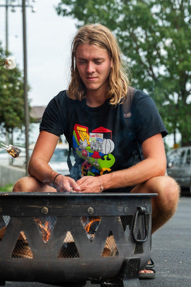 Korneel Devlies, a masters student studying industrial design, roasts a marshmallow over a campfire during the S'mores by the Campfire event outside Carmichael Gym on Tuesday, Aug. 22, 2023. The event was hosted by Outdoor Adventures as a part of Wolfpack Welcome Week.
