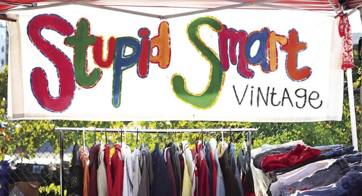 The Stupid Smart Vintage banner hangs across the back of the tent at the Super Smart Vintage pop-up at the September Sunset Market hosted by Thrift-A-Bull in Durham on Saturday, Sept. 17, 2023. Super Smart Vintage is a vintage clothing brand created and operated by NC State students Sarah Harte and Liz Edwards. Harte and Edwards are both studying fashion and textile management with a concentration in brand management.