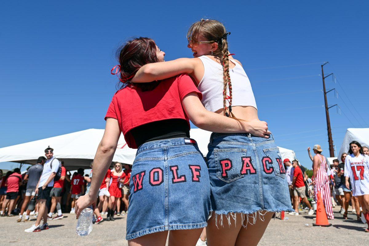 Hannah Stevens, a fourth-year in fashion and textile management, and Sophie Rutkowski, a third-year in business administration, laugh before posing for a photo with their matching skirts during the tailgate at the fairgrounds lot outside of Carter-Finley Stadium on Saturday, Sept. 16, 2023. Students were tailgating for the football game against VMI.&#160;