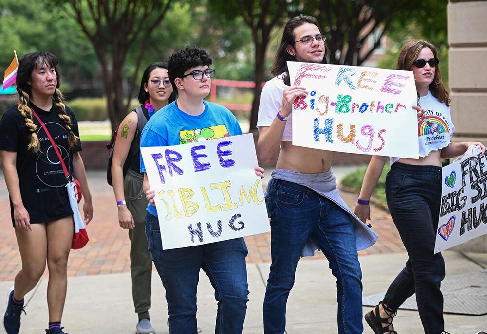 Students hold signs offering free hugs during the PrideFest parade around campus at Stafford Commons on Monday, Oct. 3, 2023. PrideFest was a celebration of NC State's LGBTQ+ community. Students walked around campus holding signs and being cheered on by students and faculty. Before the parade, students decorated signs and t-shirts.