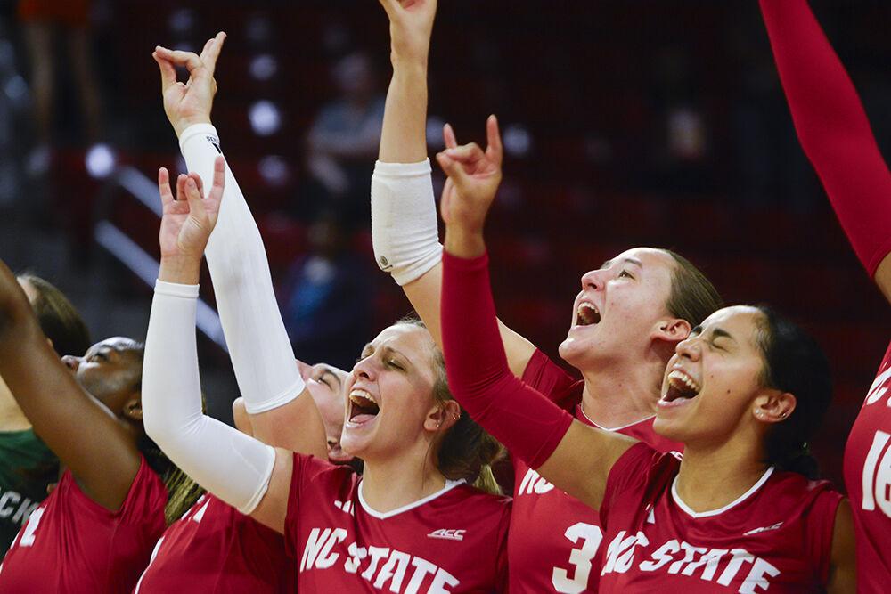 The NC State women's volleyball team raises wolfies during the match against Louisville in Reynolds Coliseum on Sunday, Oct. 1, 2023. NC State beat Louisville 3-1.