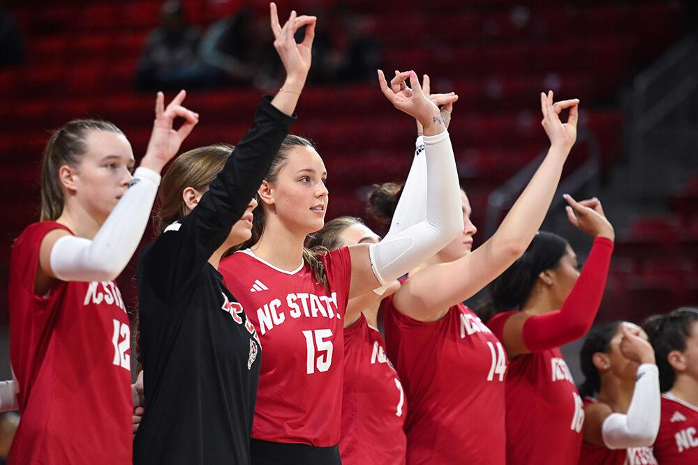 The NC State volleyball team hold up "wolfies" at the end of the match against Pitt at Reynolds Coliseum on Friday, Oct. 20, 2023. NC State lost to Pitt 3-0.