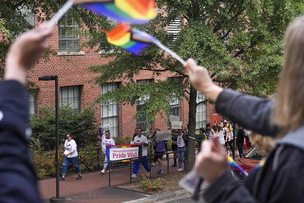 NC State community members participating in the Pride Walk pass by the College of Sciences staff as they wave flags outside of Riddick Hall on Monday, Oct. 3rd, 2022. Participators in the walk were met with support from NC State's colleges, which waved on the walkers and gave away stickers and posters.