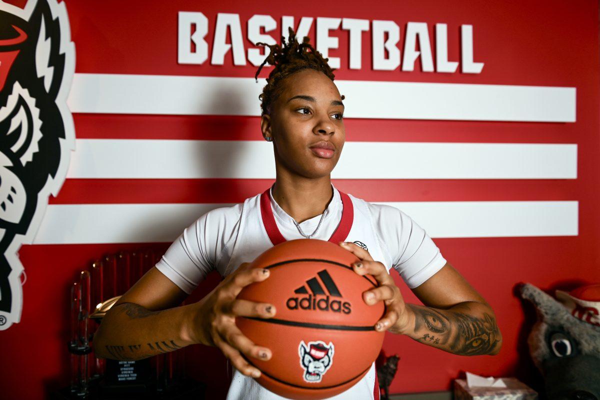 Junior guard Aziaha James poses for a portrait in front of women's basketball display in Reynolds Coliseum on Thursday, Oct. 19, 2023.