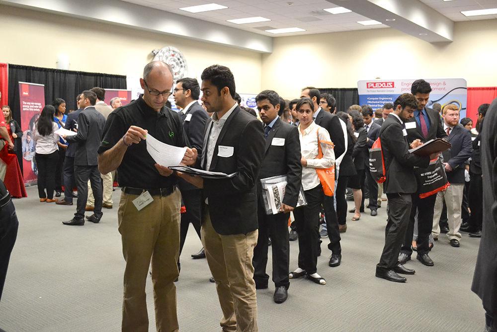 Rishi Arun Jain, a graduate student studying computer science, talks to Corey Newport, a manager of software at Nimble Storage, at the NC State Spring Career Fair in the McKimmon Center. Jain came to the career fair seeking a permanent job in either software development or data analysis.