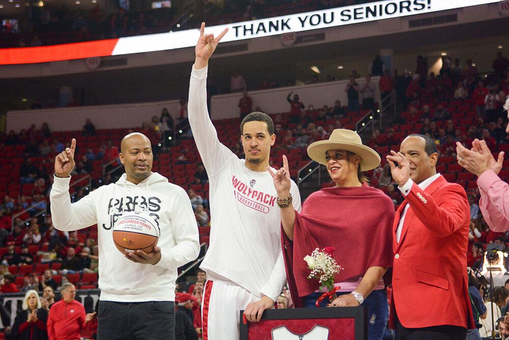 Senior forward Jericole Hellems throws up wolfies with his parents, Elizabeth Squibb and Torano Hellems, and coach Kevin Keatts to celebrate senior day before the game against the University of North Carolina in PNC Arena on Saturday, Feb. 26, 2022.