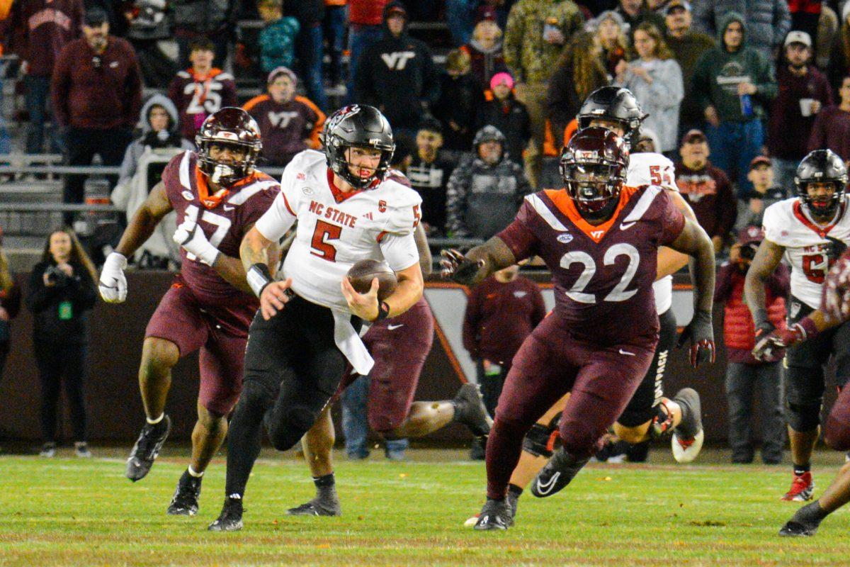 Graduate quarterback Brennan Armstrong dodges opposing players as he runs down the field during the game against Virginia Tech at Lane Stadium on Saturday, Nov. 18, 2023. Wolfpack beat the Hokies 35-28.