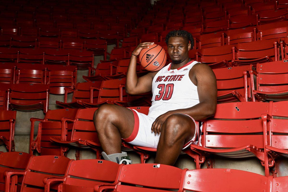 Graduate forward DJ Burns poses for a portrait in the stands of Reynolds Coliseum on Thursday, Oct. 19, 2023.