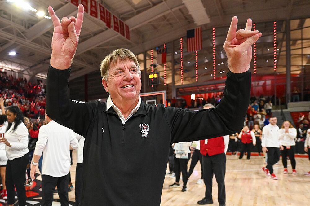 Head Coach Wes Moore holds up "wolfies" to the crowd after the NC State Women's Basketball team's win over the UConn Huskies in Reynolds Coliseum on Sunday, Nov. 12, 2023. The Wolfpack beat the Huskies 92-81.