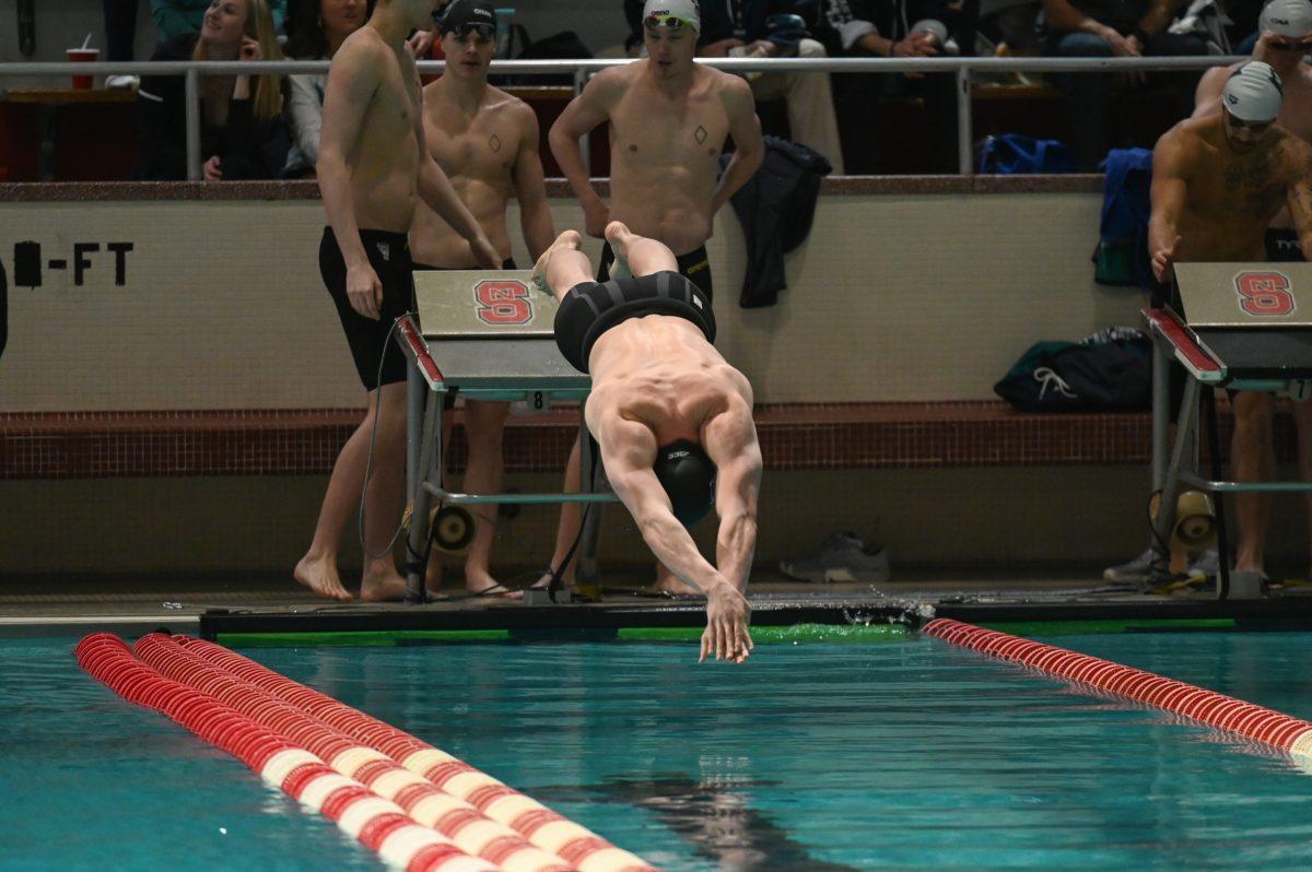 Sophomore Arsenio Bustos dives from starting block the in the men's 200 yard freestyle relay during the NC State Wolfpack's swim and dive meet against the UNC-Wilmington Seahawks at the Willis R. Casey Aquatics Center on Friday, Jan. 27, 2023. The Wolfpack men beat the Seahawks 160-126.