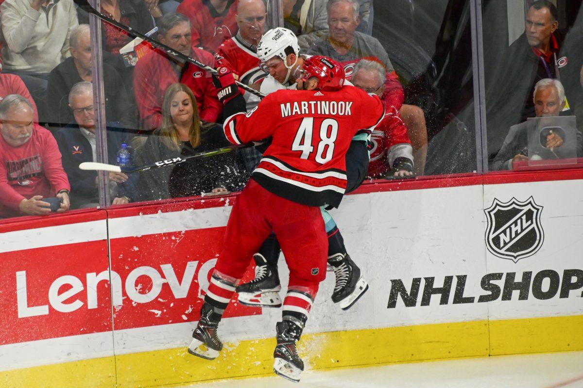 Carolina Hurricanes left wing Jordan Martinook hits an opponent into the boards during the game against the Seattle Kraken on Thursday, Oct. 26, 2023. The Hurricanes beat the Kraken 3-2 in overtime.