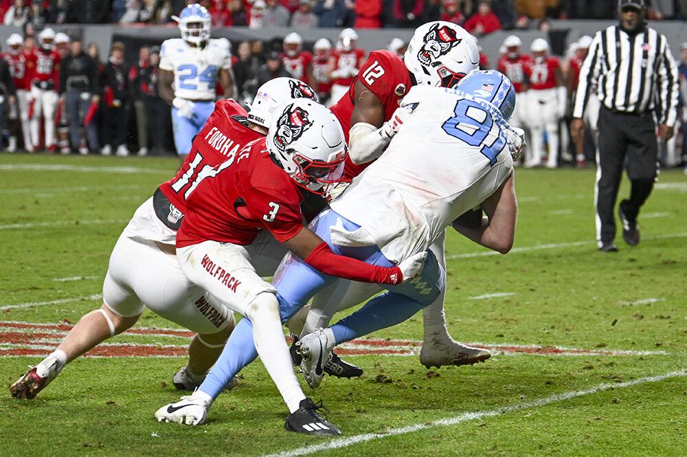 (From left) redshirt sophomore linebacker Caden Fordham, junior cornerback Aydan White and junior safety Devan Boykin bring down their opponent during the game against UNC-Chapel Hill in Carter-Finley Stadium on Saturday, Nov. 25, 2023. NC State beat UNC-Chapel Hill 39-20.