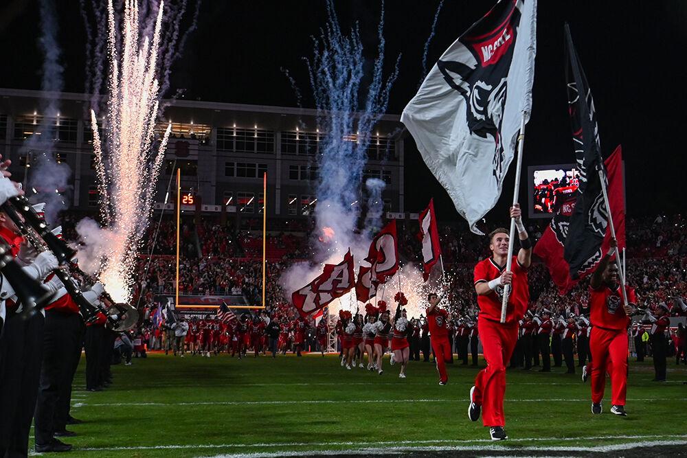 The cheerleading team runs across the field leading in the football team before the game against Miami at Carter-Finley Stadium on Saturday, Nov. 4, 2023. NC State beat Miami 20-6.