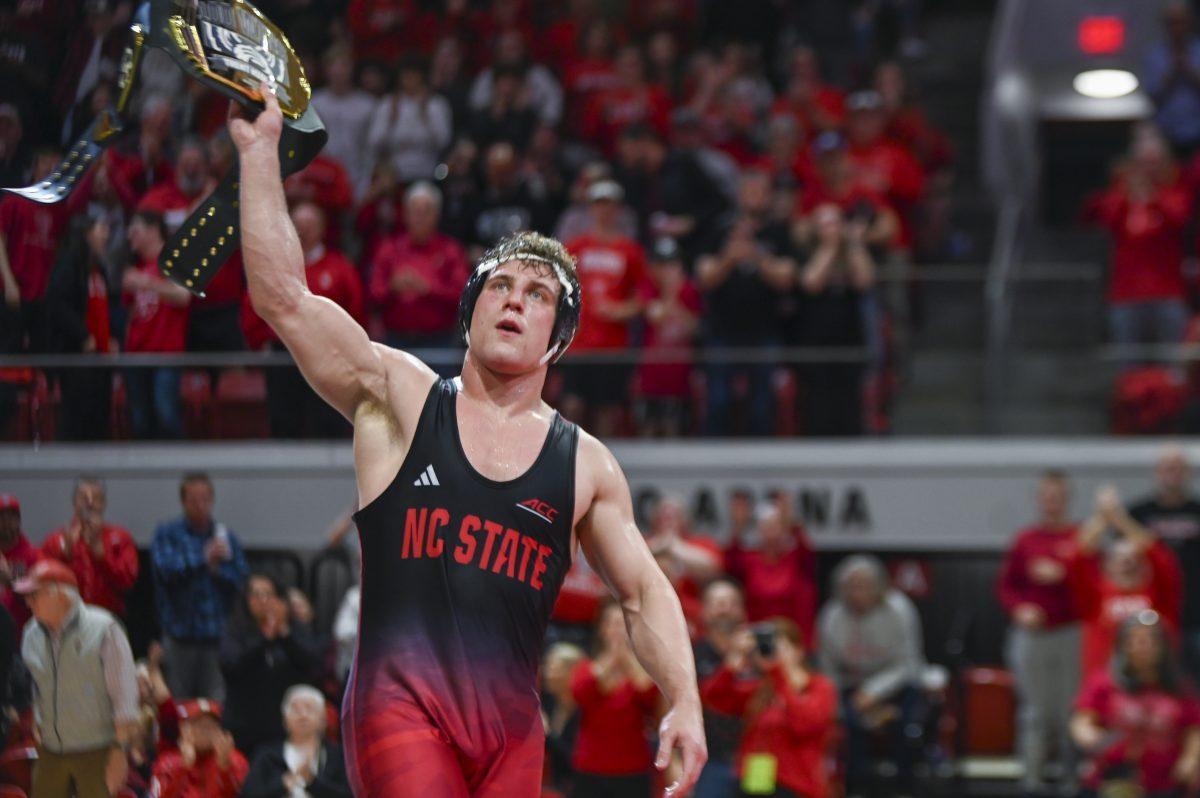 Redshirt senior Trent Hidlay holds up a belt after securing his 100th career win during the wrestling match against Virginia Tech in Reynolds Coliseum on Sunday, Feb. 23, 2024. Hidlay won the 197 bout 18-3 by technicall fall. NC State beat Virginia Tech 20-12
