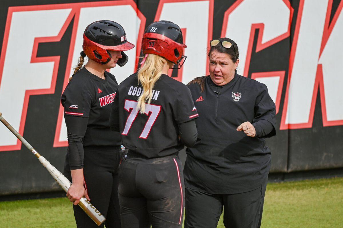 Head coach Lindsay Leftwich (right) talks to junior infielder Hannah Goodwin (center) and redshirt sophomore infielder Michele Tarpey (left) before they bat during the game against Elon at Dail Softball Stadium on Saturday, Feb. 17, 2024. The Wolfpack defeated the Phoenix 5-2.