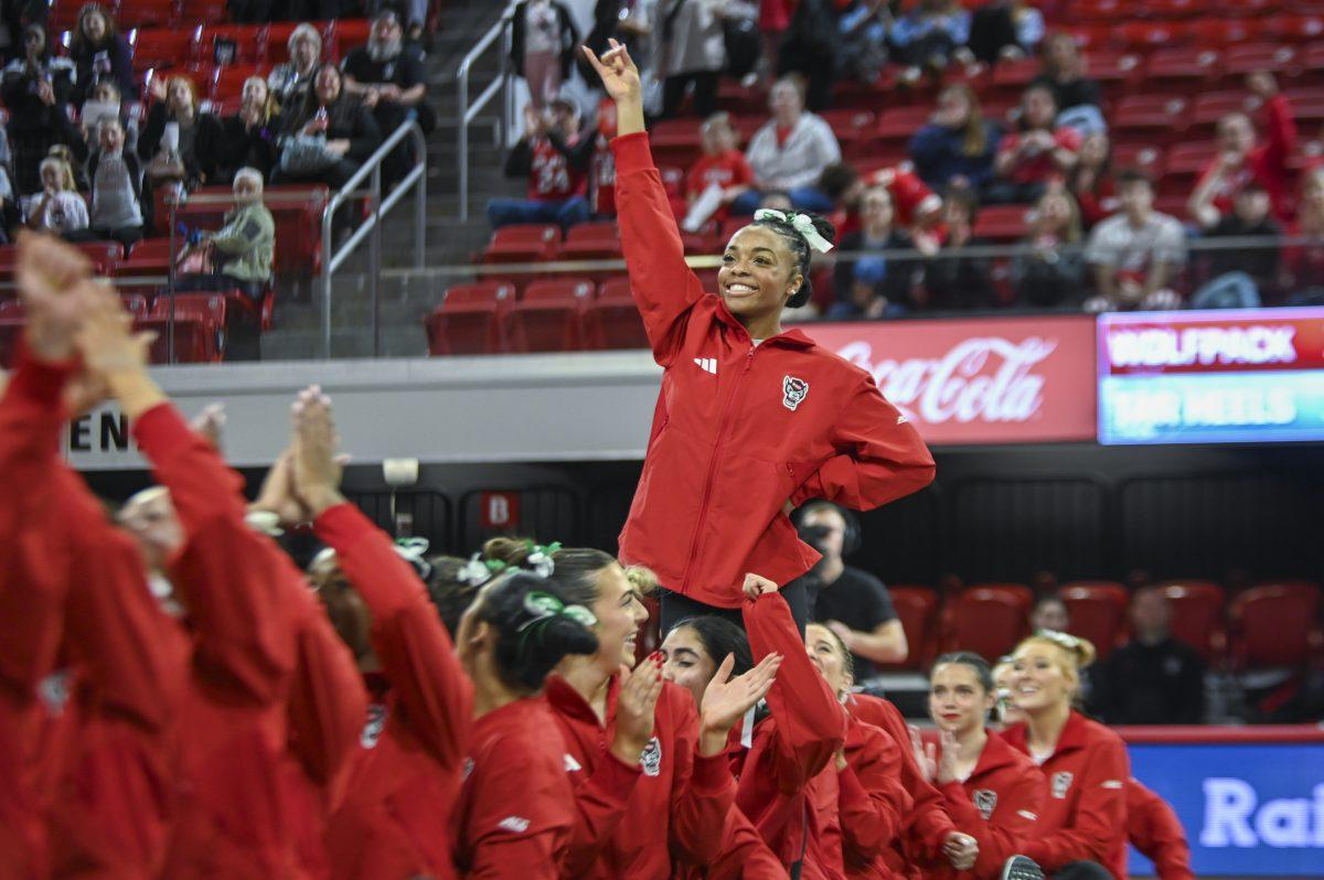 Freshman Ashley Knight holds up a "wolfie" after being announced the winner of the vault event during the meet against UNC-Chapel Hill in Reynolds Coliseum on Sunday, Feb. 11, 2024. NC State beat UNC 196.725-194.925