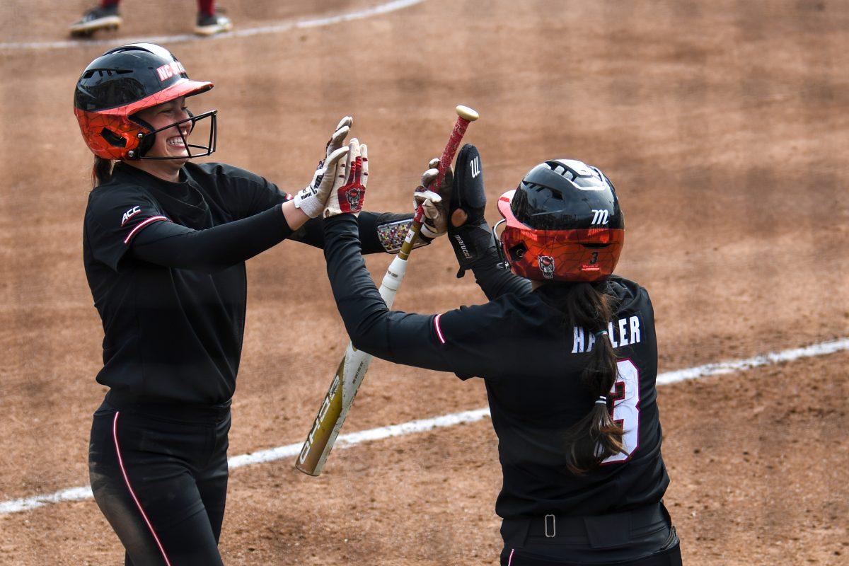Junior infielder Taylor Ensley (left) high-fives sophomore catcher Amanda Hasler (right) during the game against Elon at Dail Softball Stadium on Saturday, Feb. 17, 2024. NC State won the game 5-2.