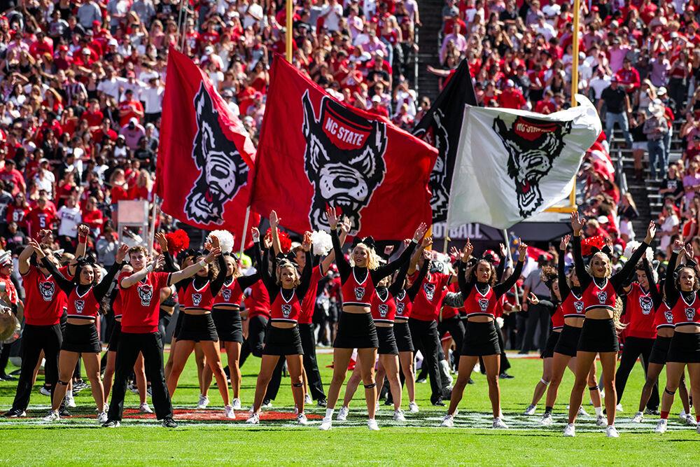 The NC State cheerleaders wave their arms and flags before the game against Marshall at Carter-Finley Stadium on Saturday, Oct. 7, 2023. NC State beat Marshall 48-41.