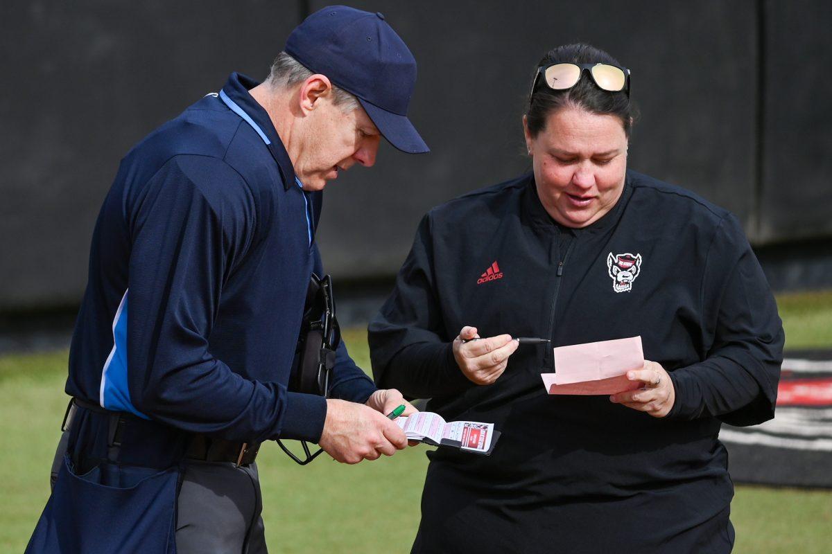 Head coach Lindsay Leftwich (right) and umpire James Cooper (left) discuss the scores during the game against Elon at Dail Softball Stadium on Saturday, Feb. 17, 2024. The Wolfpack defeated the Phoenix 5-2.