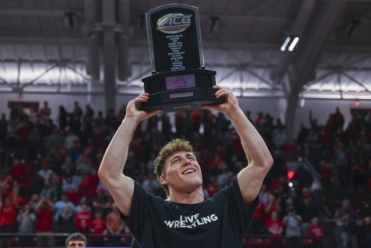 Redshirt senior Trent Hidlay holds up a trophy after the NC State wrestling team won the ACC regular season dual meet championship in Reynolds Coliseum on Friday, Feb. 23, 2024. NC State beat Virginia Tech 20-12.