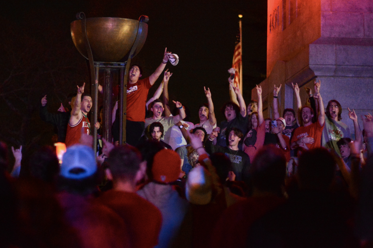 Fans raise wolfies as they sing The Star-Spangled Banner at the Belltower on Saturday, March 16, 2024. NC State men's basketball's Saturday victory is its first ACC championship win since 1987.