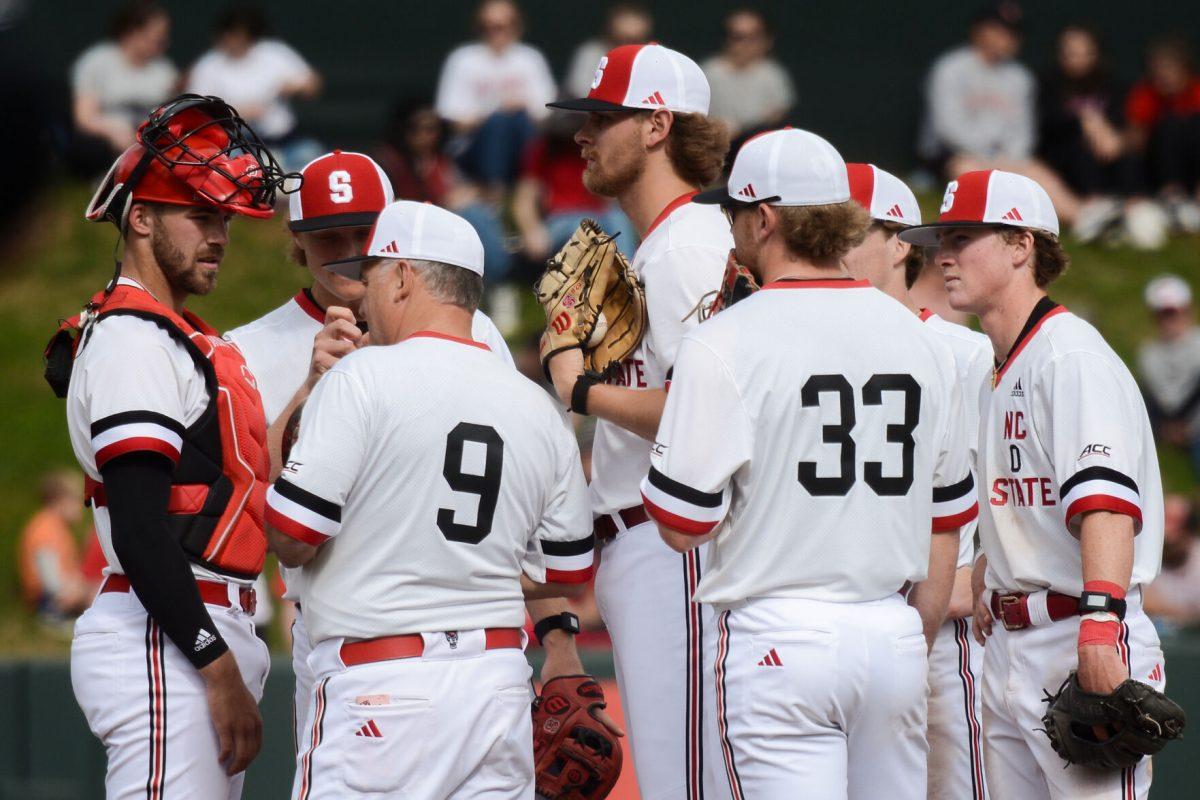 Head coach Elliott Avent discusses strategy with players during a timeout during the game against Duke at Doak Field at Dail Park on Saturday, March 23, 2024. NC State defeated Duke 9-8.