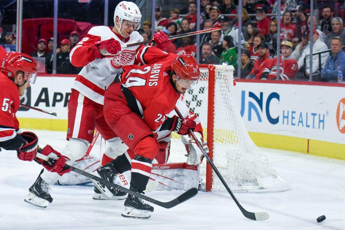 Center Seth Jarvis is bumped by Red Wings defenseman Olli Maatta while going for the puck during the game in PNC Arena on Thursday, March 28, 2024. The Hurricanes defeated the Red Wings 4-0.