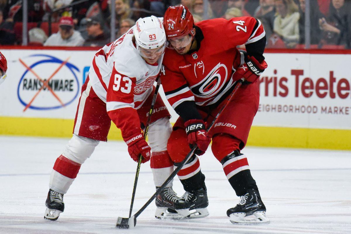 Center Seth Jarvis and Red Wings right wing Alex DeBrincat fight for the puck during the game in PNC Arena on Thursday, March 28, 2024. The Hurricanes defeated the Red Wings 4-0.