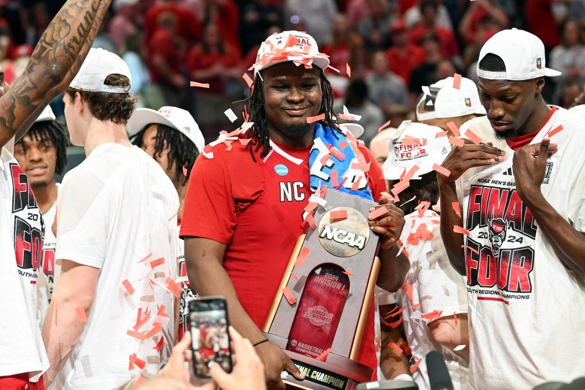 Graduate forward DJ Burns smiles while holding the South Regional trophy after winning the NCAA Tournament Elite 8 game against Duke at American Airlines Center in Dallas on Sunday, March 31, 2024. Burns led in scoring with 29 points. NC State beat Duke 76-64 to advance to the Final Four.