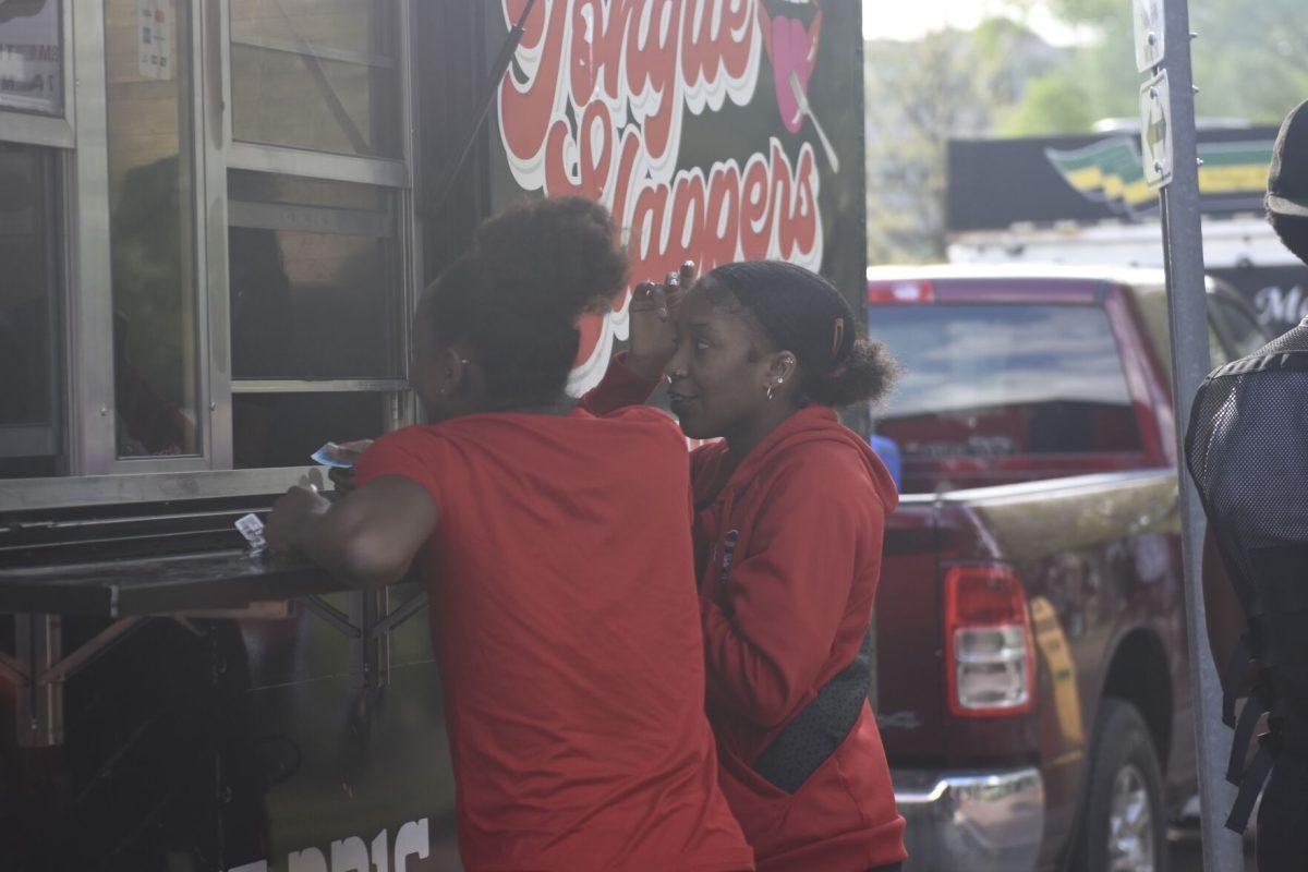 Imunique Archie, a fourth year studying animal science and Zahra Bichara stand to get food from Toungue Slappers at the Stomp the Yard Darty in Harris Field on Friday, April 12, 2024. The darty marked the fifth day of Pan-Afrikan Week.