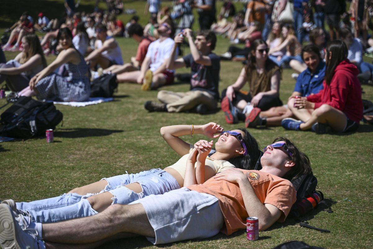 Sunida Siphanthone, a second-year studying chemical engineering, and Peter Roberts, a second-year in civil engineering, watch the eclipse together during the solar eclipse viewing party on Harris Field on Monday, April 8, 2024. While North Carolina experienced a partial solar eclipse, 13 states including Maine and New Mexico experienced a total eclipse. The next eclipse is expected to be in 2044.