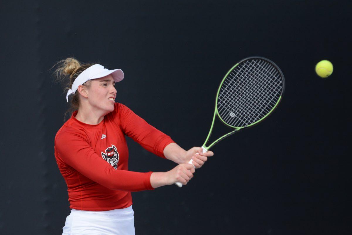 Senior Amelia Rajecki backhands the ball during the match against Miami at Dail Outdoor Tennis Stadium on Friday, April 5, 2024. Rajecki won her singles match and celebrated her one hundredth career win. NC State beat Miami 4-3.