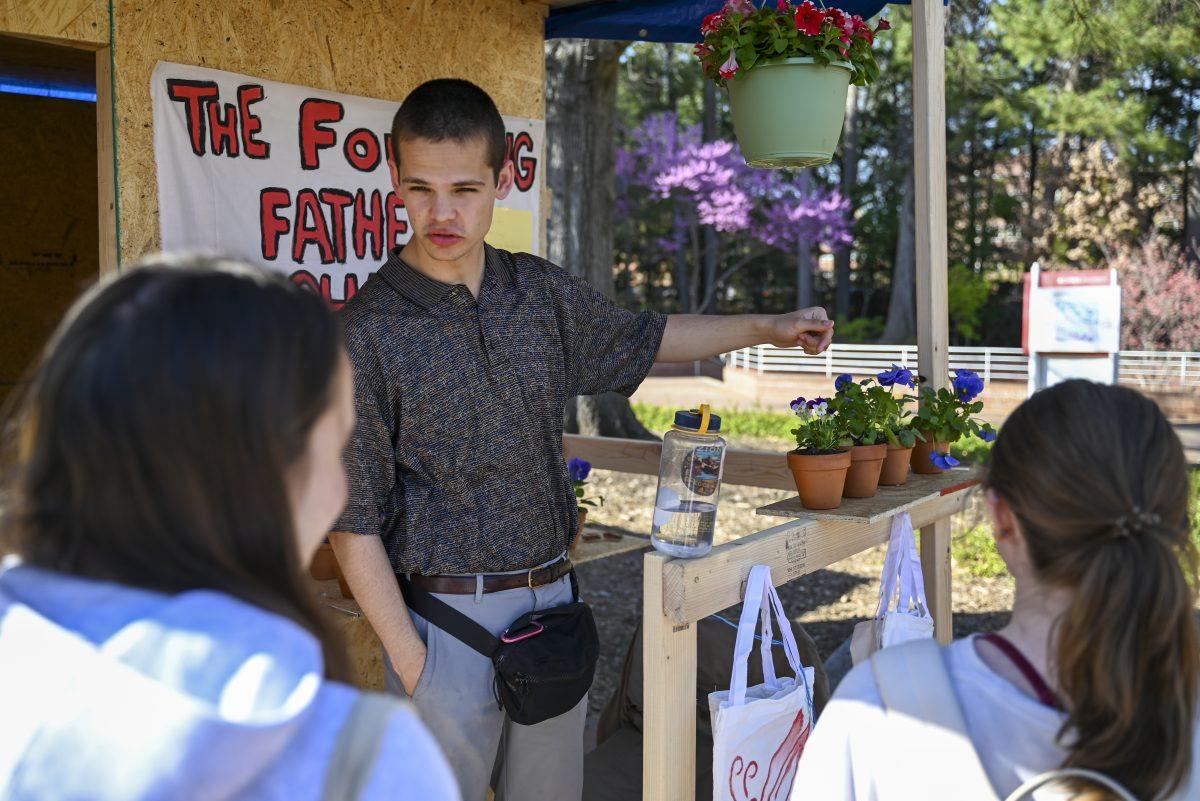 Caden Miller, a second-year studying industrial engineering and philosophy, tries to sell plants outside the Founding Father Scholars shack during Shack-a-thon at Wolf Plaza on Monday, March 25, 2024. The Founding Father Scholars consist of the Thomas Jefferson, Alexander Hamilton and Benjamin Franklin Scholars program. The three organizations sold potted plants and tote bags to raise funds for Habtiat for Humanity.