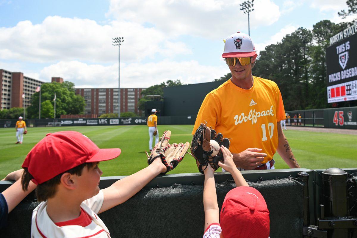 Freshman pitcher Chance Mako hands kids a baseball before the inaugural Victory Over Cancer game against Ball State at Doak Field at Dail Park on Sunday, April 28, 2024. NC State raised $50,860 for pediatric cancer research. NC State beat Ball State 11-3 and swept the series.