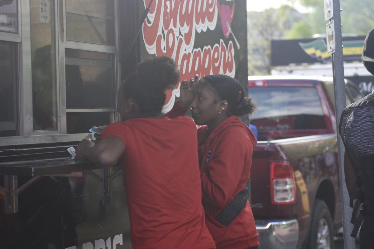 Imunique Archie, a fourth year studying animal science and Zahra Bichara stand to get food from Toungue Slappers at the Stomp the Yard Darty in Harris Field on Friday, April 12, 2024. The darty marked the fifth day of Pan-Afrikan Week.