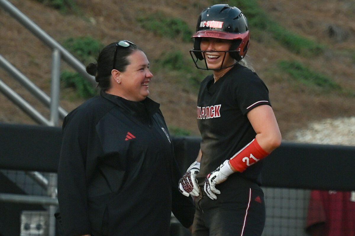 Sophomore utility player and pitcher Madison Inscoe (right) laughs with the head coach Lindsay Leftwich (left) after being declared safe on third base during the game against Elon at Dail Softball Stadium on Tuesday, April 2, 2024. Inscoe had three at bats, one home run, two hits and pitched one inning. NC state won the game 12-2.